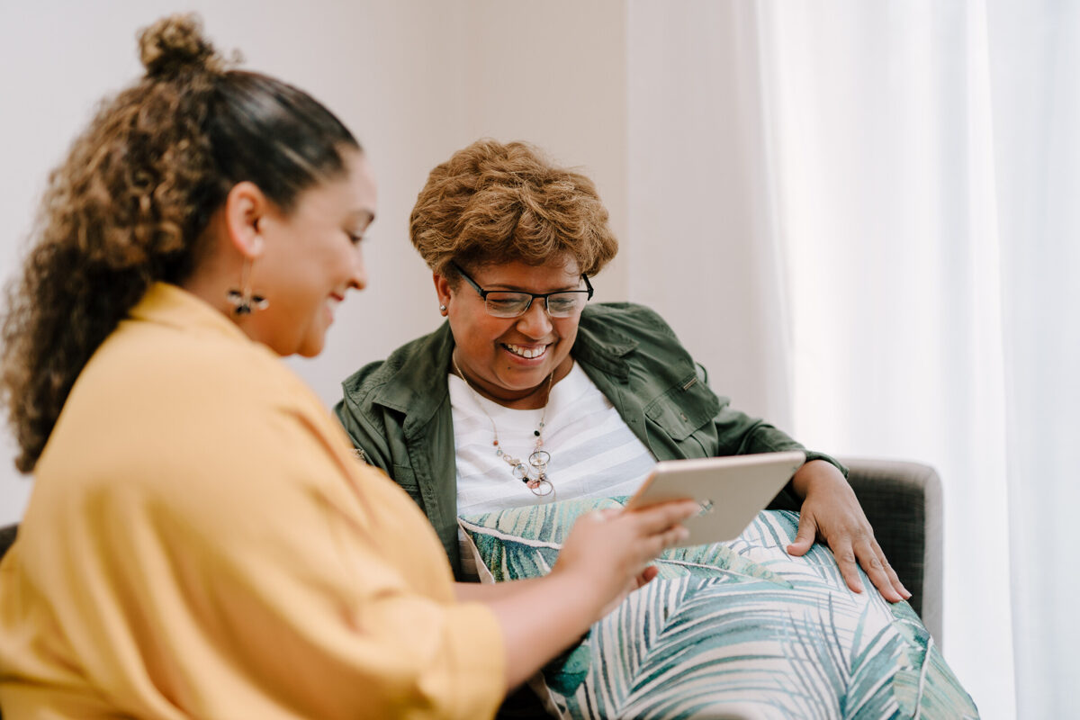 Two women sat looking at a electronic tablet