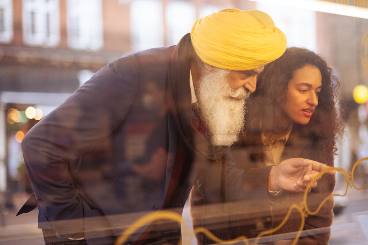 Man and woman looking in a window of shop pointing to an item